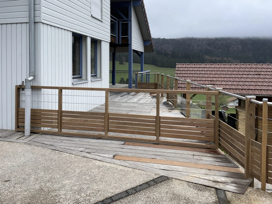 Terrasse extérieure en bois avec garde-corps horizontal à lames, maison moderne à bardage blanc vertical