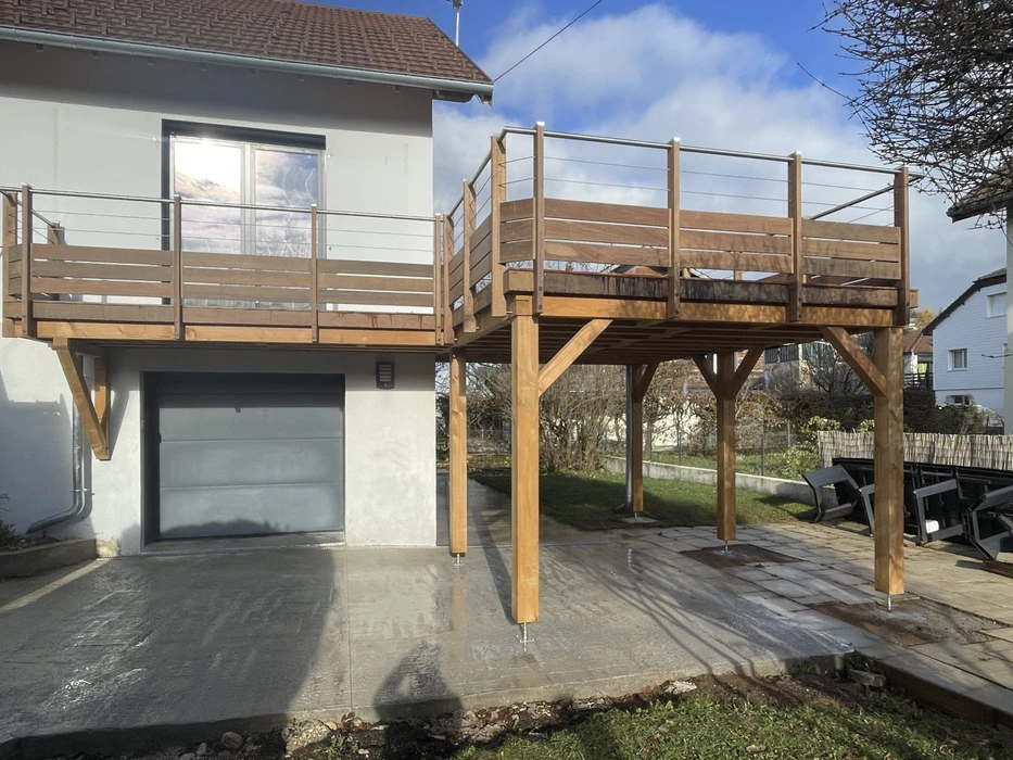 Terrasse extérieure surélevée en bois avec garde-corps à barreaudage horizontal, supportée par poteaux et consoles