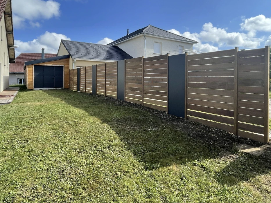 Escalier extérieur en bois avec terrasse et garde-corps métalliques, menant à l'étage d'une maison moderne